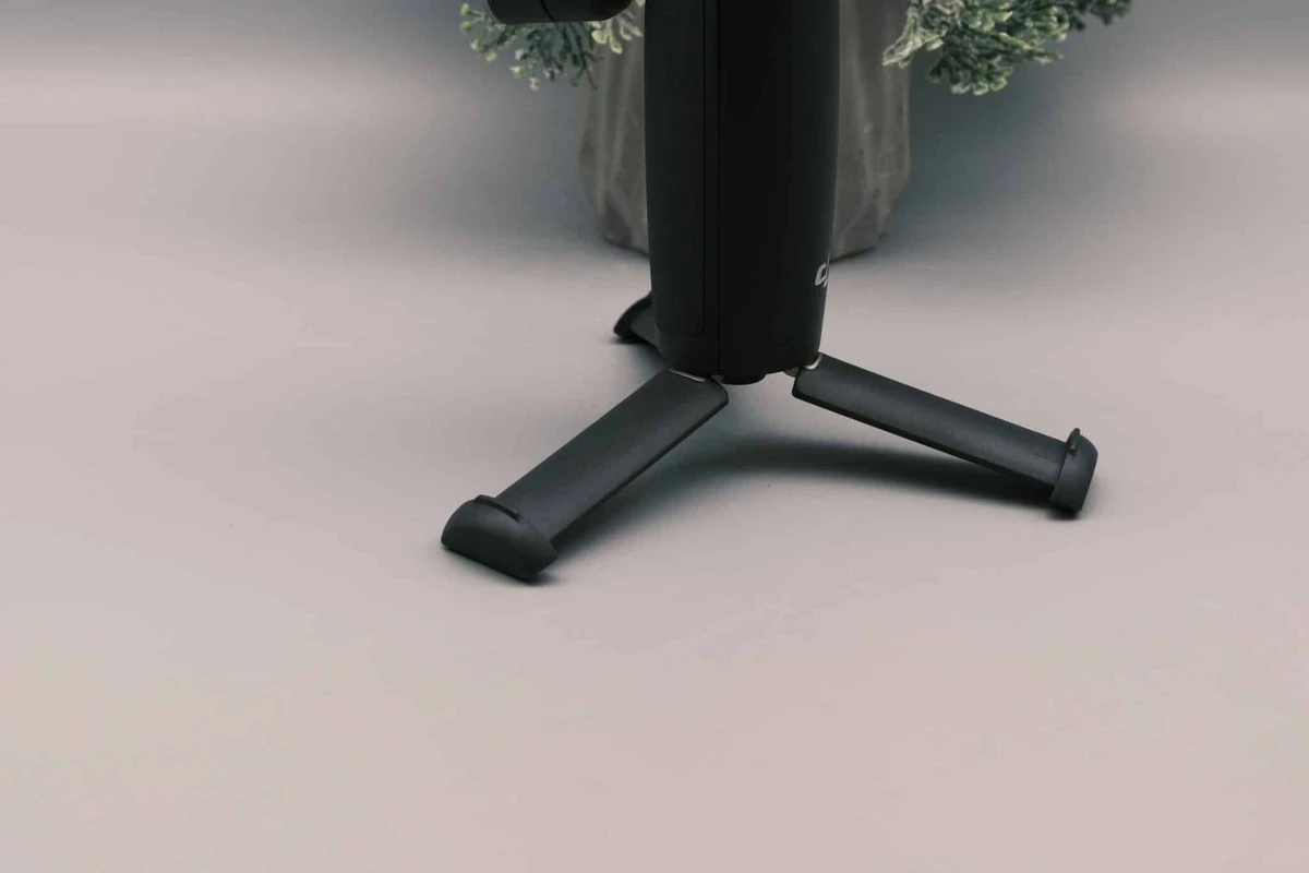 Вбудована підставка-штатив DJI Osmo Mobile 7P розкладена під ручкою стабілізатора, який стоїть на столі